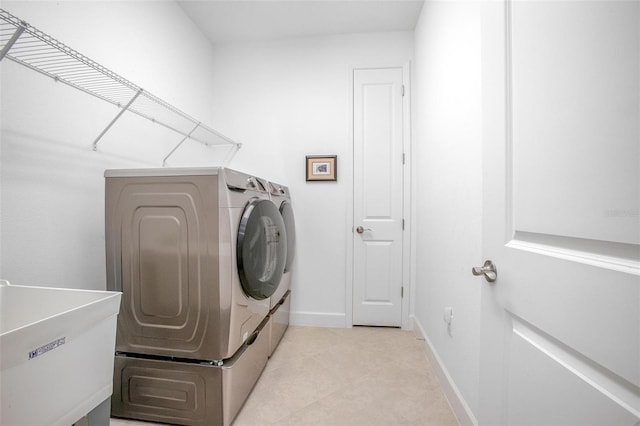 laundry area featuring laundry area, light tile patterned floors, baseboards, washer and dryer, and a sink