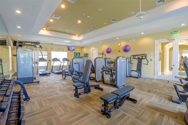 workout area with light carpet, a raised ceiling, and visible vents