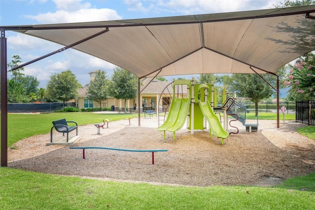 community jungle gym featuring fence and a lawn