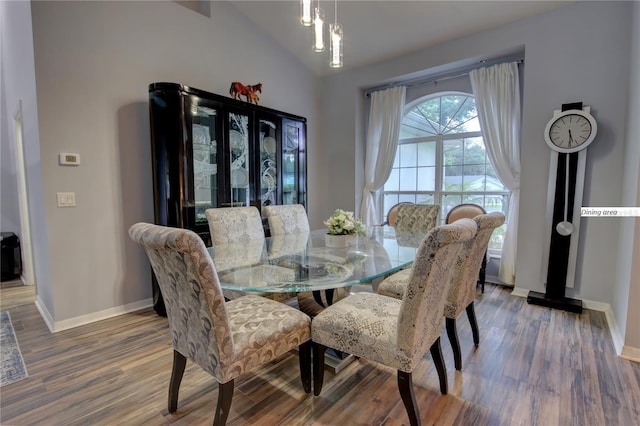 dining room featuring lofted ceiling, wood finished floors, and baseboards