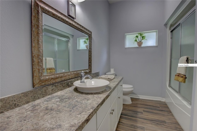 full bathroom with shower / bath combination with glass door, toilet, vanity, wood finished floors, and baseboards