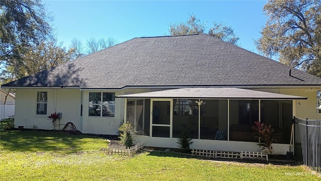 back of house featuring a sunroom, roof with shingles, a lawn, and fence