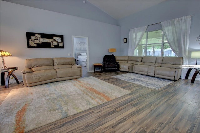 living area with high vaulted ceiling, wood finished floors, and baseboards