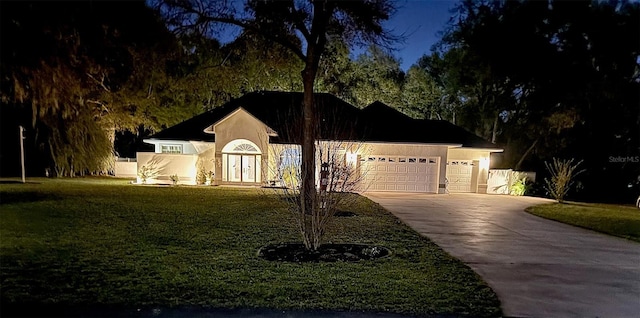 ranch-style home featuring stucco siding, a front yard, an attached garage, and driveway