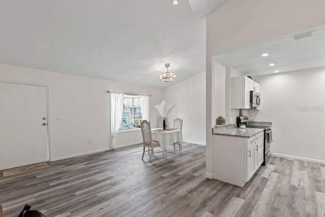 kitchen featuring white cabinetry, appliances with stainless steel finishes, hardwood / wood-style flooring, and light stone counters