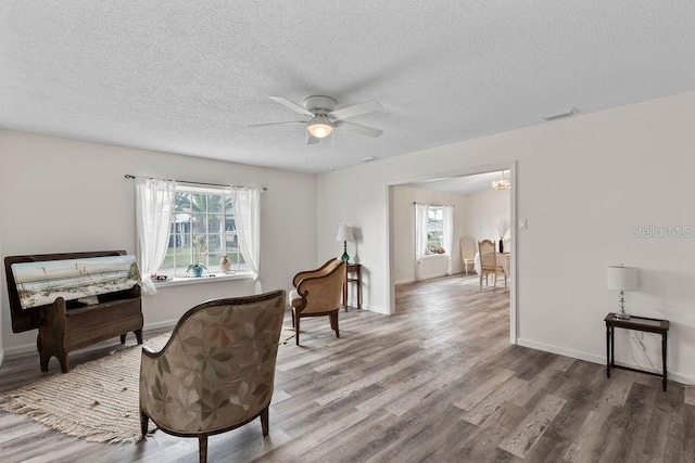 sitting room featuring ceiling fan, wood-type flooring, and a textured ceiling