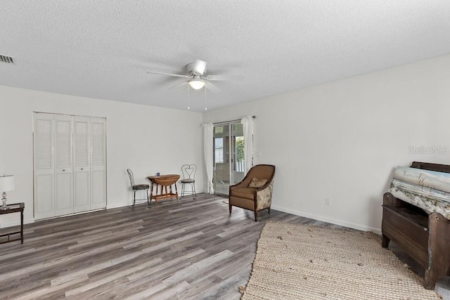 sitting room featuring hardwood / wood-style flooring, ceiling fan, and a textured ceiling