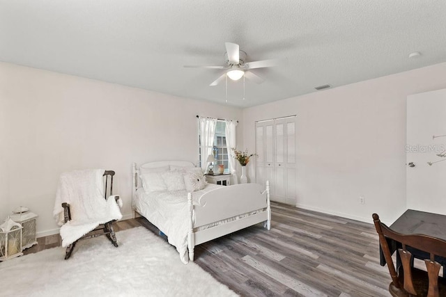 bedroom featuring a textured ceiling, a closet, dark hardwood / wood-style floors, and ceiling fan