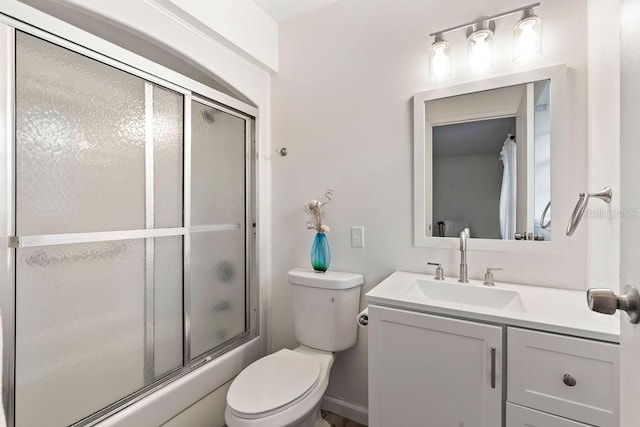 full bathroom with enclosed tub / shower combo, vanity, and toilet