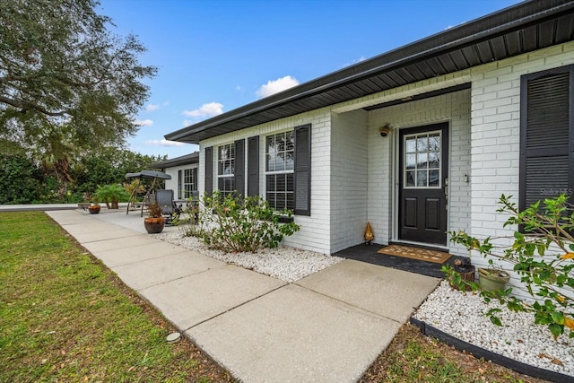 view of exterior entry featuring brick siding