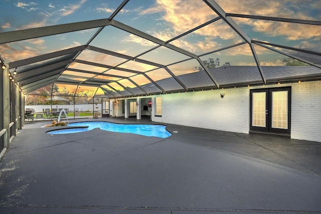 pool at dusk with a patio, glass enclosure, fence, french doors, and a fenced in pool