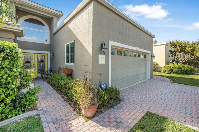 view of property exterior with a garage, decorative driveway, and stucco siding