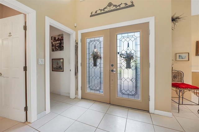 foyer entrance featuring french doors, baseboards, and light tile patterned floors