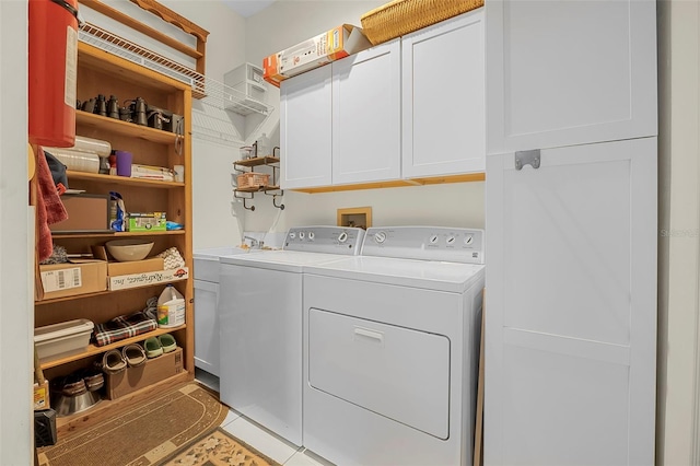 washroom featuring cabinet space, light tile patterned floors, and washing machine and clothes dryer