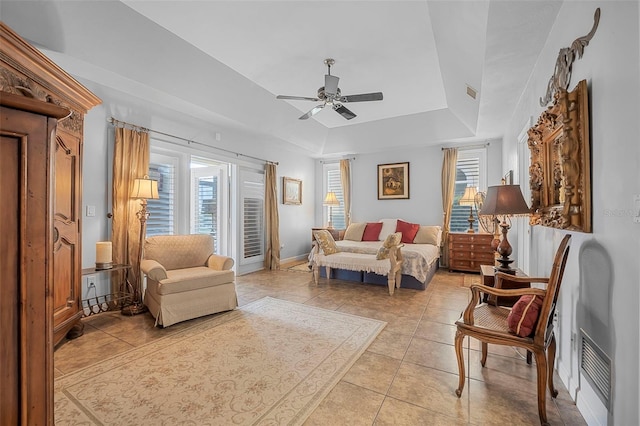 sitting room with light tile patterned floors, a tray ceiling, a ceiling fan, and baseboards