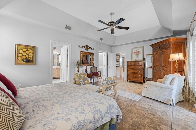 bedroom featuring ceiling fan, ensuite bath, visible vents, and a raised ceiling