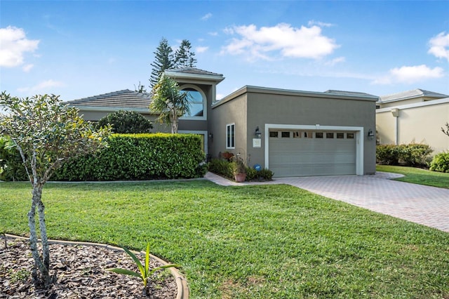 view of front of house with a garage, decorative driveway, a front yard, and stucco siding