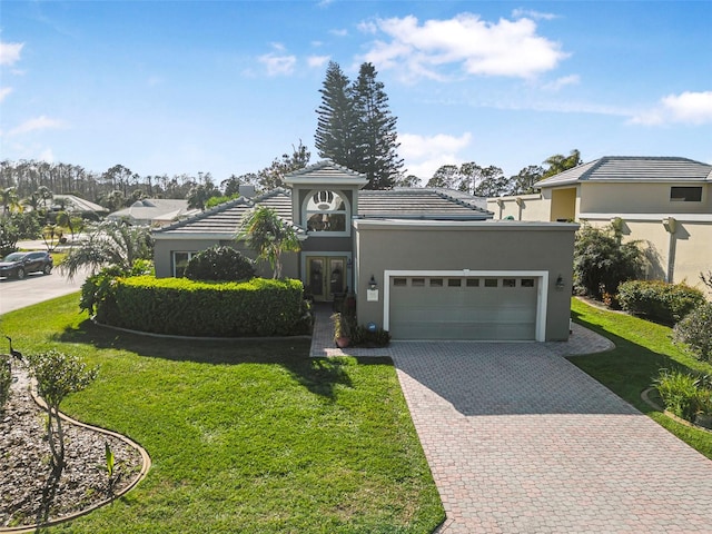 view of front of property featuring a garage, decorative driveway, a front lawn, and stucco siding