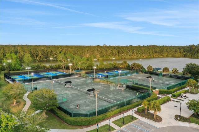 view of sport court featuring a water view and a wooded view