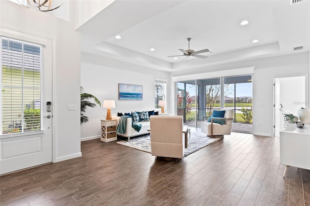 living room featuring dark hardwood / wood-style floors, ceiling fan, and a raised ceiling