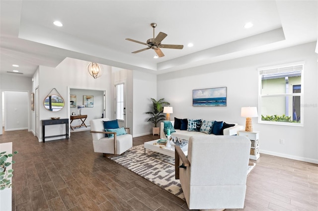 living room with a raised ceiling, wood-type flooring, and a healthy amount of sunlight