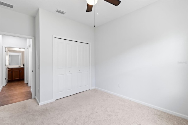 unfurnished bedroom with ceiling fan, light carpet, and a closet