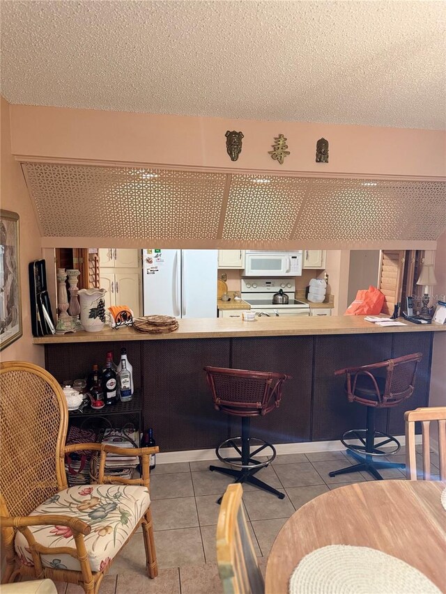 interior space featuring white appliances, light tile patterned flooring, and a textured ceiling