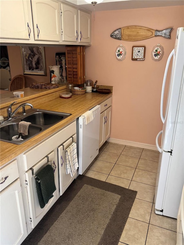 kitchen with white appliances, white cabinetry, sink, and light tile patterned floors