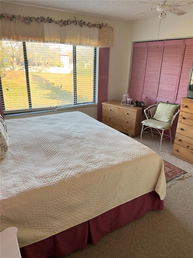 bedroom with a textured ceiling, a closet, carpet, and ceiling fan