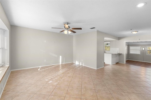 unfurnished living room featuring ceiling fan, light tile patterned flooring, visible vents, and baseboards