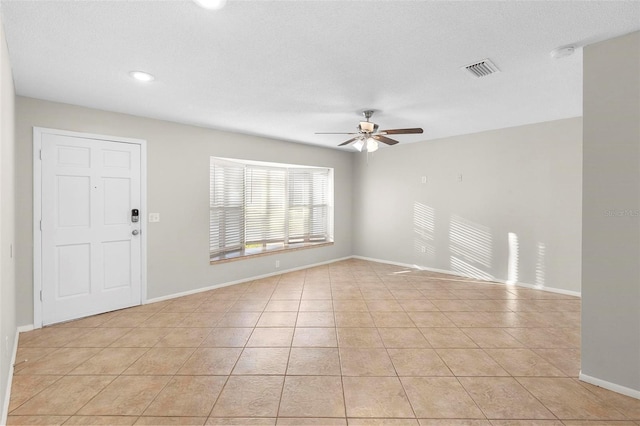 interior space with light tile patterned floors, a textured ceiling, visible vents, baseboards, and a ceiling fan