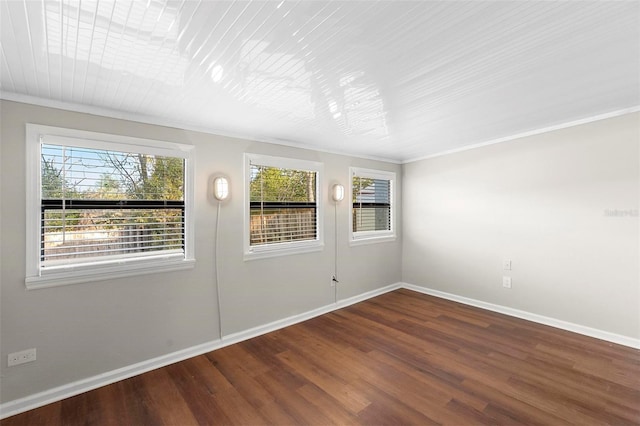 empty room featuring ornamental molding, wood finished floors, and baseboards