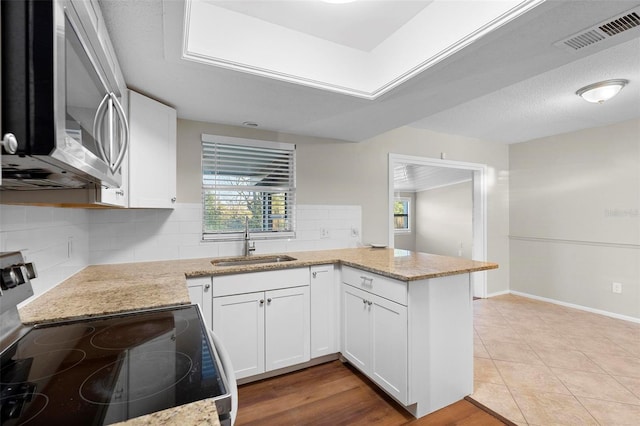 kitchen with visible vents, white cabinets, light stone counters, appliances with stainless steel finishes, and a sink