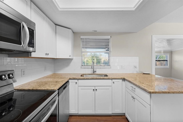 kitchen with appliances with stainless steel finishes, white cabinets, a sink, and light stone countertops