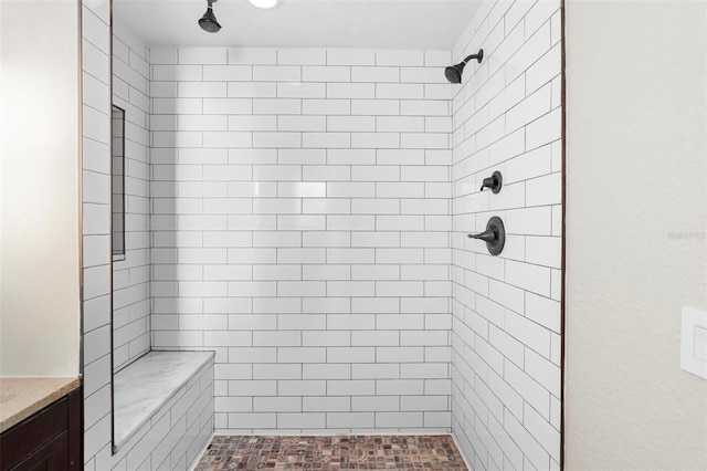 bathroom featuring a tile shower and vanity