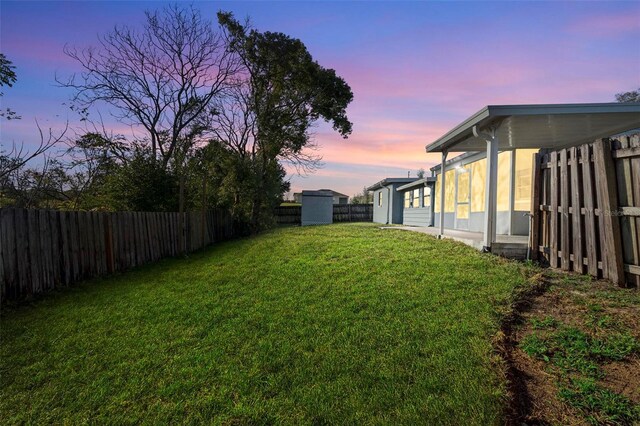 yard at dusk featuring a fenced backyard