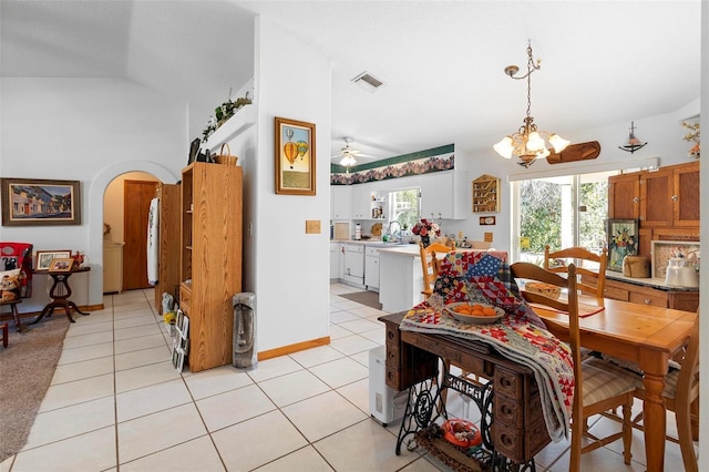 tiled dining area with ceiling fan with notable chandelier, vaulted ceiling, and sink