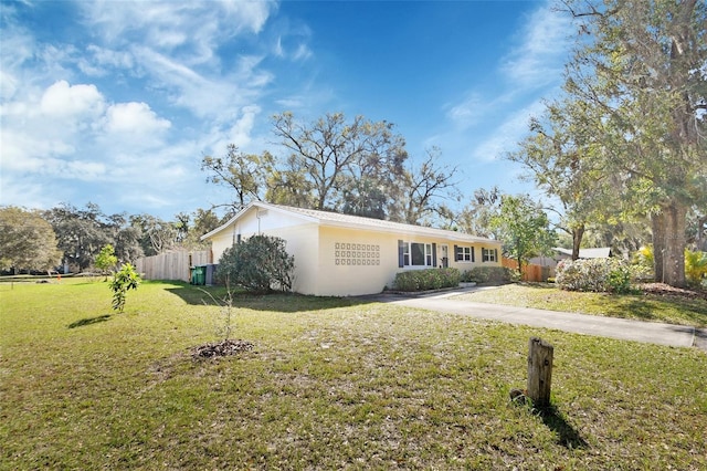 single story home with driveway, a front yard, fence, and stucco siding