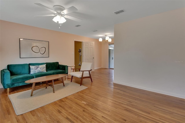 living room with ceiling fan, baseboards, visible vents, and light wood-style floors