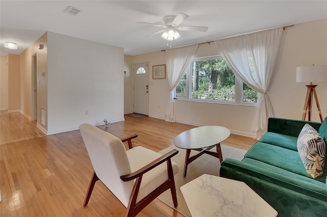 living room with ceiling fan, light wood-type flooring, visible vents, and baseboards