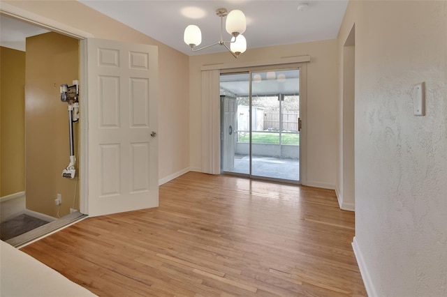 unfurnished dining area with baseboards, light wood-style flooring, and an inviting chandelier