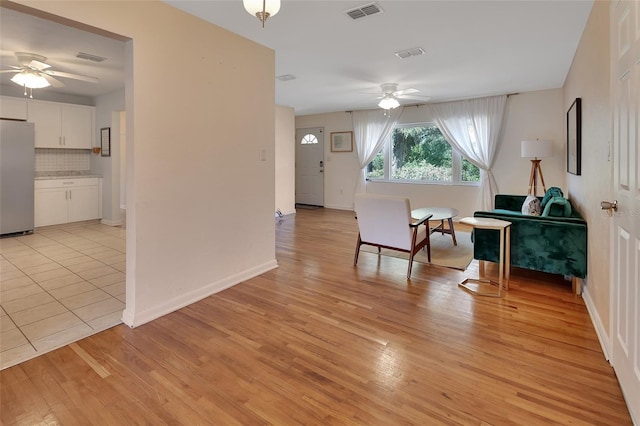 unfurnished room with a ceiling fan, visible vents, light wood-style flooring, and baseboards