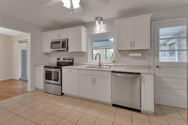 kitchen featuring appliances with stainless steel finishes, a sink, white cabinetry, and decorative backsplash