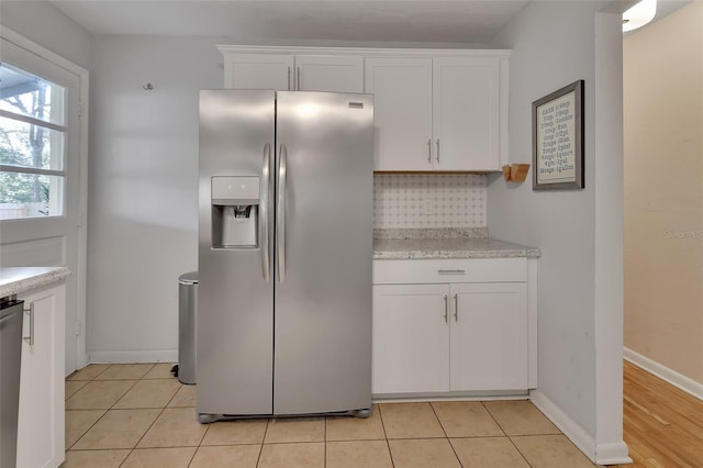 kitchen with light tile patterned floors, baseboards, appliances with stainless steel finishes, light countertops, and white cabinetry