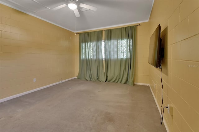 carpeted empty room with concrete block wall and ceiling fan