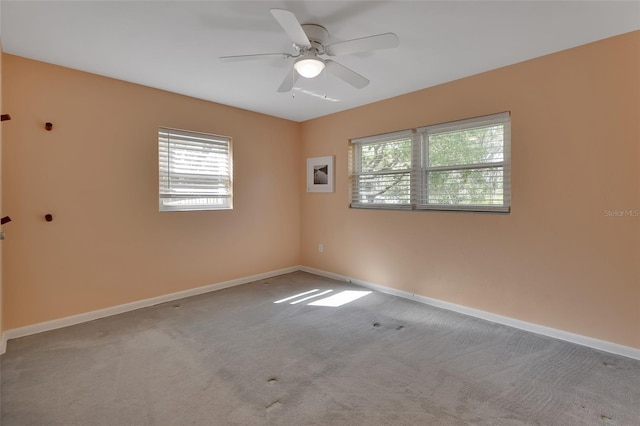 spare room featuring light carpet, ceiling fan, and baseboards