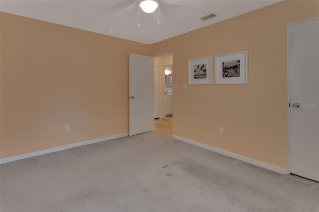 empty room with light carpet, a ceiling fan, visible vents, and baseboards