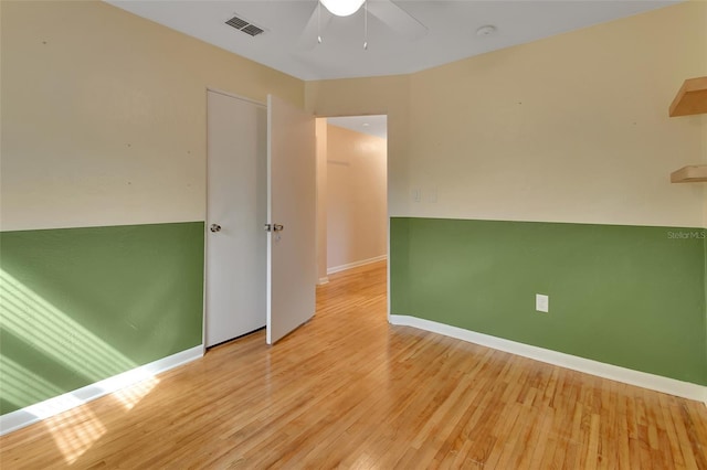 empty room featuring light wood-type flooring, baseboards, visible vents, and a ceiling fan