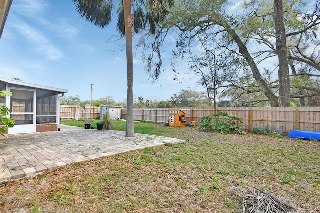 view of yard featuring an outbuilding, a sunroom, a patio area, a shed, and a fenced backyard