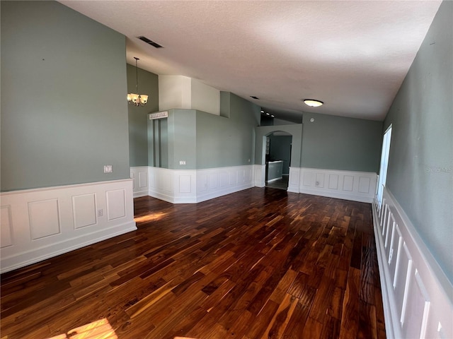 spare room with arched walkways, lofted ceiling, visible vents, wood finished floors, and a chandelier